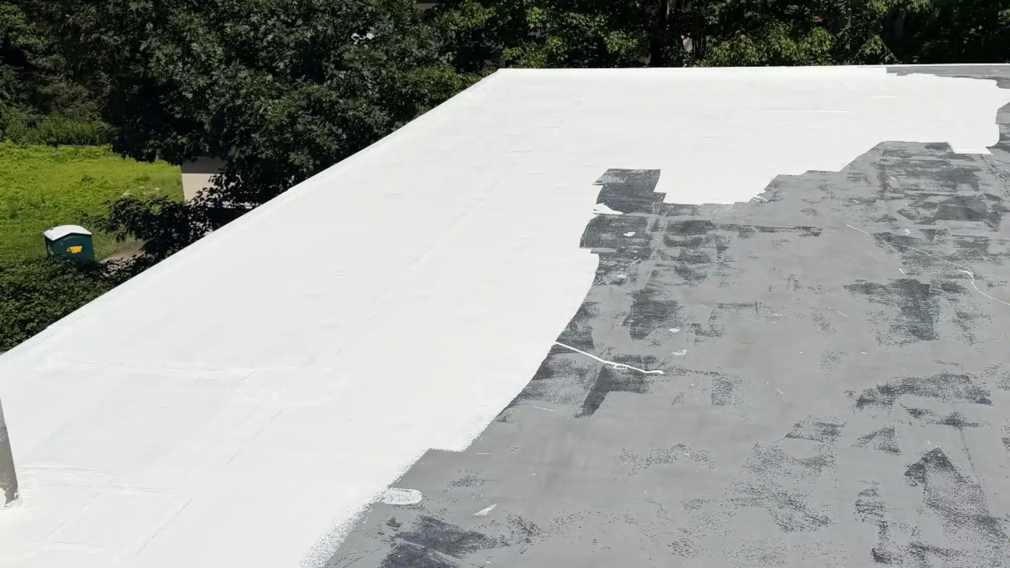 Commercial flat roof receiving a protective white coating during professional roofing work